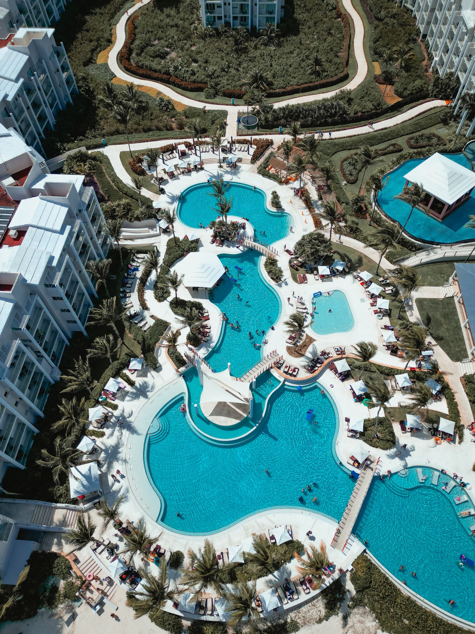 Vue aérienne d'un hôtel tropical, piscines turquoise et végétation luxuriante